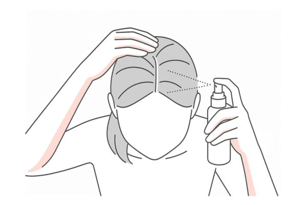 スプレー式育毛剤を分け目に噴射している使用イメージ（女性の頭頂部）